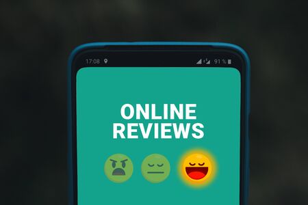 Online Reviews Services or Organization. Mobile phone screen with emoticons smiles. Quality evaluation of service, hotel or restaurantの写真素材