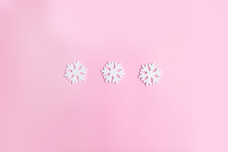 Three snowflakes on a pink background, top view, flat lay