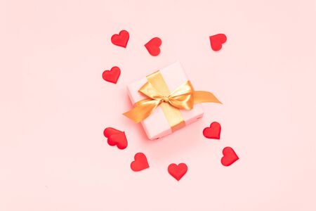 Valentine's day composition or banner of surprise gifts with gold bow and heart shape on a pink background. Flat lay, top view, copy space.の写真素材