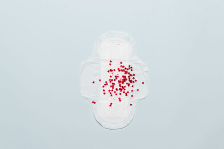 Menstruation pad with red stars glitters on blue background. Women critical days, gynecological...