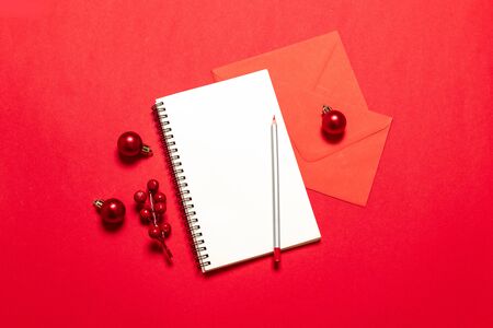 Top view goals list with notebook,pen, christmas balls, mail card on red desk. Planning concept.の写真素材