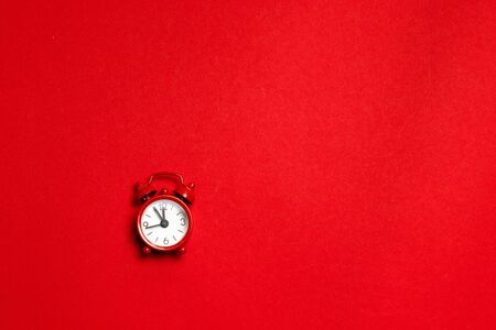 Red alarm clock in a minimal style on a red background. Flat lay.の写真素材