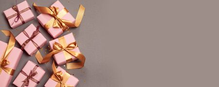 Top view festive composition with beautiful gifts wrapped in festive paper, gold ribbon and gold star confetti on a gray background.の写真素材