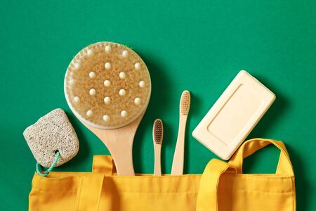 Concept of zero waste and caring for environment. Textile eco friendly bags, soap, bamboo toothbrush, soap accessories on a green background. Top view or flat layの写真素材