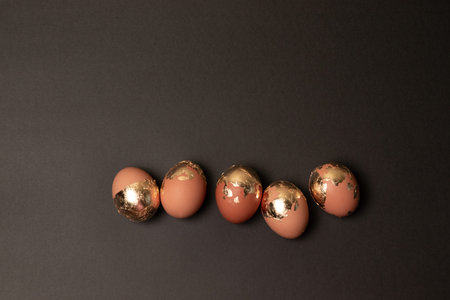 Top view of golden decorated easter eggs on dark black background