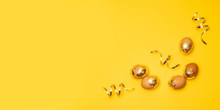 Top view of golden eggs and serpentine on a yellow background. Can be used for web banner, advertisement, poster, discount voucher.の写真素材