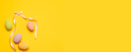 Happy easter composition with eggs decor and silk ribbon on a yellow background with place for text. Can be used for web banner, poster, voucher.の写真素材