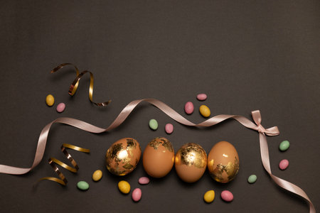 Happy easter concept. Golden eggs, color candy on a dark background, Layout or template for banner,...