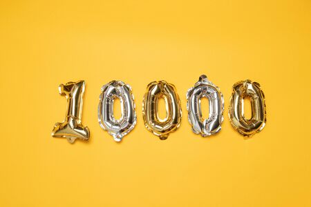Gold and silvr 10,000 number balloons on yellow background. Followers and Subscription Conceptの写真素材