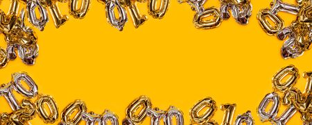 Gold and silver air numbers balloons on a yellow background. Holiday composition with copyspace, top view.の写真素材