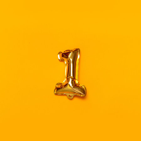 One number gold shine balloon on a yellow background. Leader or victory metaphor concept.