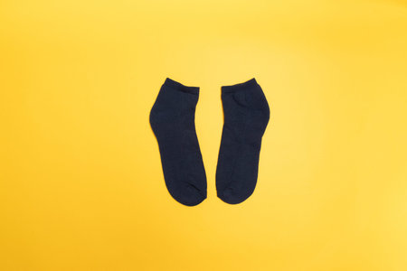 Black socks on a yellow background, top view. Minimal composition