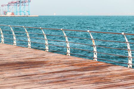 Empty promenade on a sunny day. Metal railings and wooden beams of a terrace along the sea. Langeron city beach on a sunny spring morning.の写真素材
