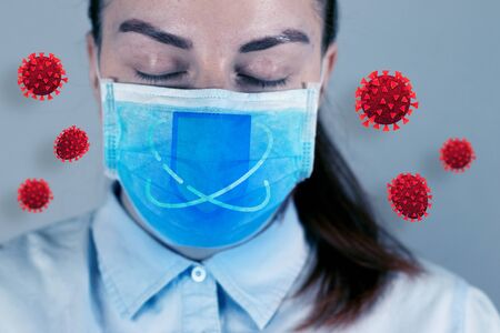 Doctor woman in medical mask and coronavirus cells in the air on gray wall with copy space. Coronavirus, covid 19 conceptの写真素材