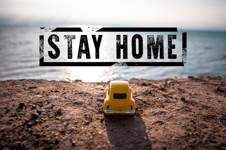 Stay home stamp text and toy car on background of a sea landscape on a sunny day. Coronavirus, covid...