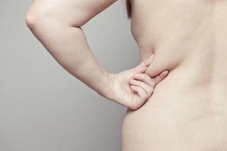 Back of the human body with folds on the back due to malnutrition and low athletic activity. Obesity and gluttony conceptの写真素材