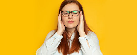 Depression unhappy woman in shirt and eyesight glasses with headache on yellow wall background....