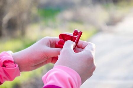 Girl takes out red wireless headphones from a case for listening and running on the streetの写真素材