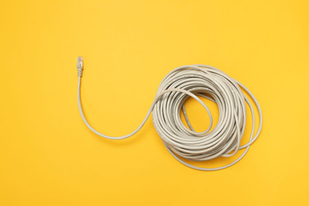 Closeup Network internet cable hank RJ45 on yellow background. Concept, flat lay.