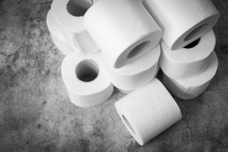 Three rolls of toilet paper on a light grey background. Basic hygiene article shortage