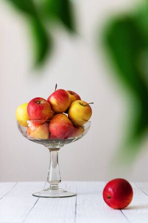 Glass plate with yellow and green apples on a table on a gray background, vertical photoの写真素材