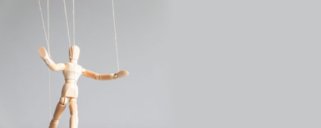 Human tree figurine with threads suspended in the air with copy space on a gray background....