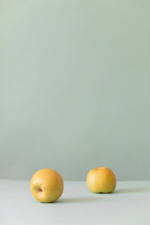 Two fresh yellow apples on a green background, vertical photoの写真素材