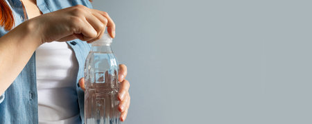 Woman hand opening water bottle in room. Thirst Concept, copyspace