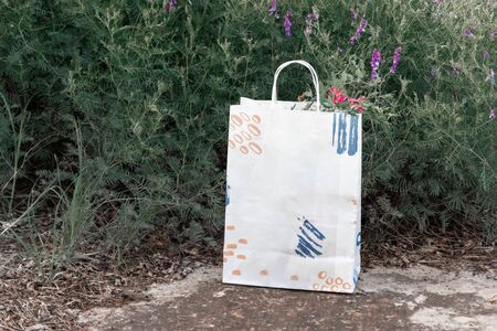 Standing white eco paper bag outside. Remote home delivery of goods and productsの写真素材