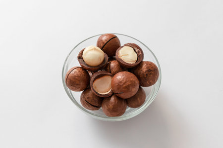 Composition with organic macadamia nut shells macadamia in glass jar on a gray backgroundの写真素材