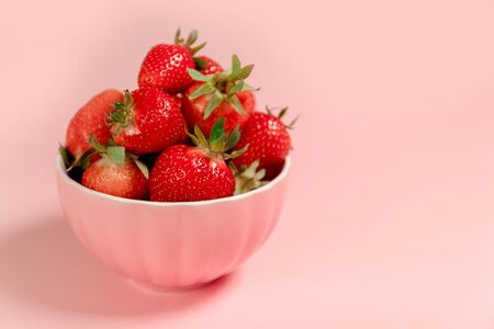 Bowl with fresh strawberries on a pink background. Summer compositionの写真素材