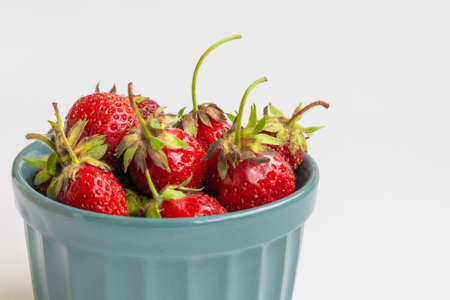Organic strawberries in a bowl on a white background. Summer compositionの写真素材