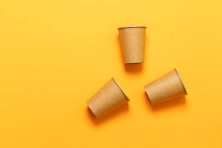Paper cups in a chaotic position on an orange background with space for text. Minimal flat layの写真素材
