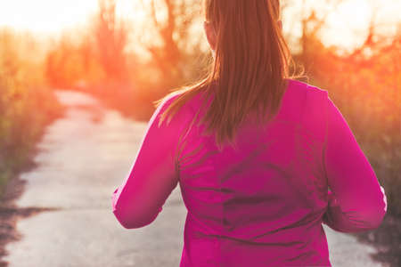 Back of woman enjoys running outdoors in a park or in the countryside.の写真素材