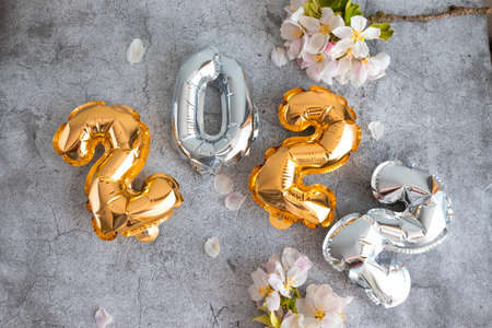 Gold and silver 2022 balloons numbers with apple tree branches on a concrete background, flat lay, top viewの写真素材