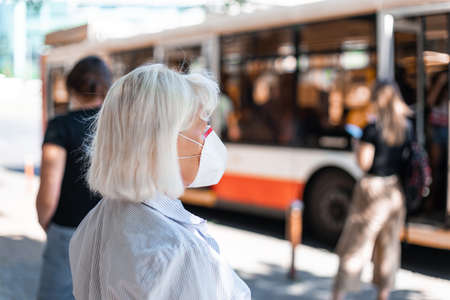 Caucasian blond woman wearing protection mask against novel coronavirus 2019-ncov at public train station, health care concept.の写真素材