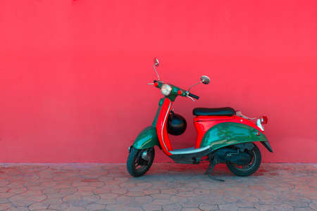Electric red green scooter parking against the background of a solid pink wall on a city street. Car sharing conceptの写真素材
