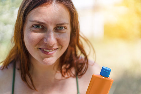 Young smile woman with bottle sunscreen solar cream uv protect on the beach