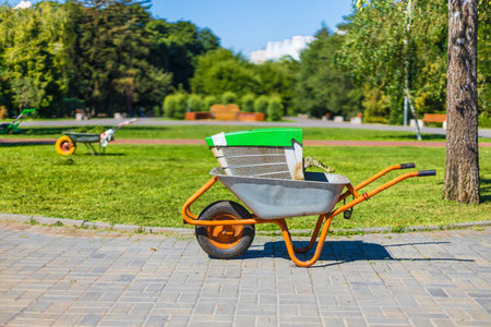 Wheelbarrow on a green grass field. Garden metal wheelbarrow cart.