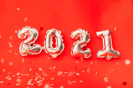 Gold helium balloons forming happy new year 2021 congratulation, christmas celebration decoration isolated on red backgroundの写真素材