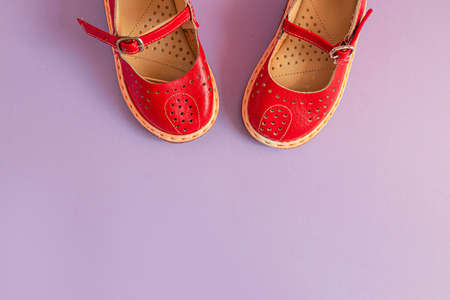 Bright red kids shoes on lilac background with copyspace. Baby clothes concept. Top view, flat layの写真素材