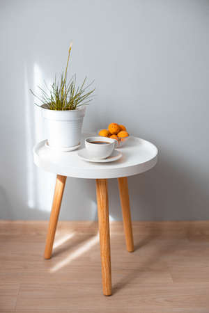 Coffee cup with plant pot on wooden coffee table in white living room interior. Vertical photoの写真素材