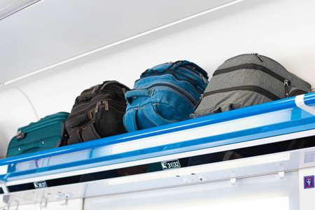 Carry-on luggage on the top shelf of the luggage compartment of an aircraft, train. Travel concept with copy spaceの写真素材