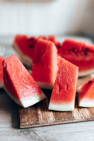 Ripe pieces of watermelon on a wooden cutting board in the kitchen. Vertical photo orientation. Food...