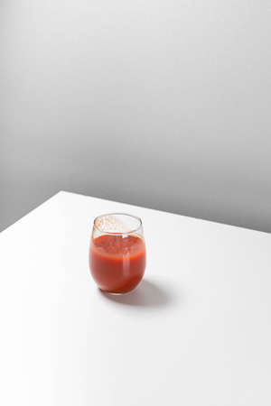 Minimal creative composition with glass of tomato juice on the table. Art geometric conceptの写真素材