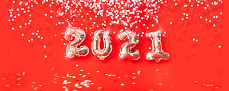 Happy new year 2021 celebration. gold foil balloons numeral 2021 and confetti on red background. 3d illustrationの写真素材