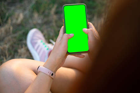 Woman hands holding black Mockup mobile phone with blank screen sitting in the park. Remote control concept. Online training for students. Online shoppingの写真素材