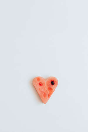 Watermelon slice in heart shape on a wooden background. Minimal art concept. Valentine's day. Flat lay, top view.の写真素材