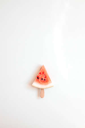 Ripe slice of watermelon in the form of a heart on a stick on a white background. Healthy food. Vertical orientationの写真素材