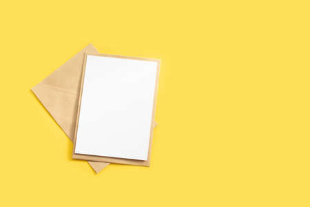 Brown kraft envelope and blank letter mockup on yellow background with place for text on postcard.の写真素材